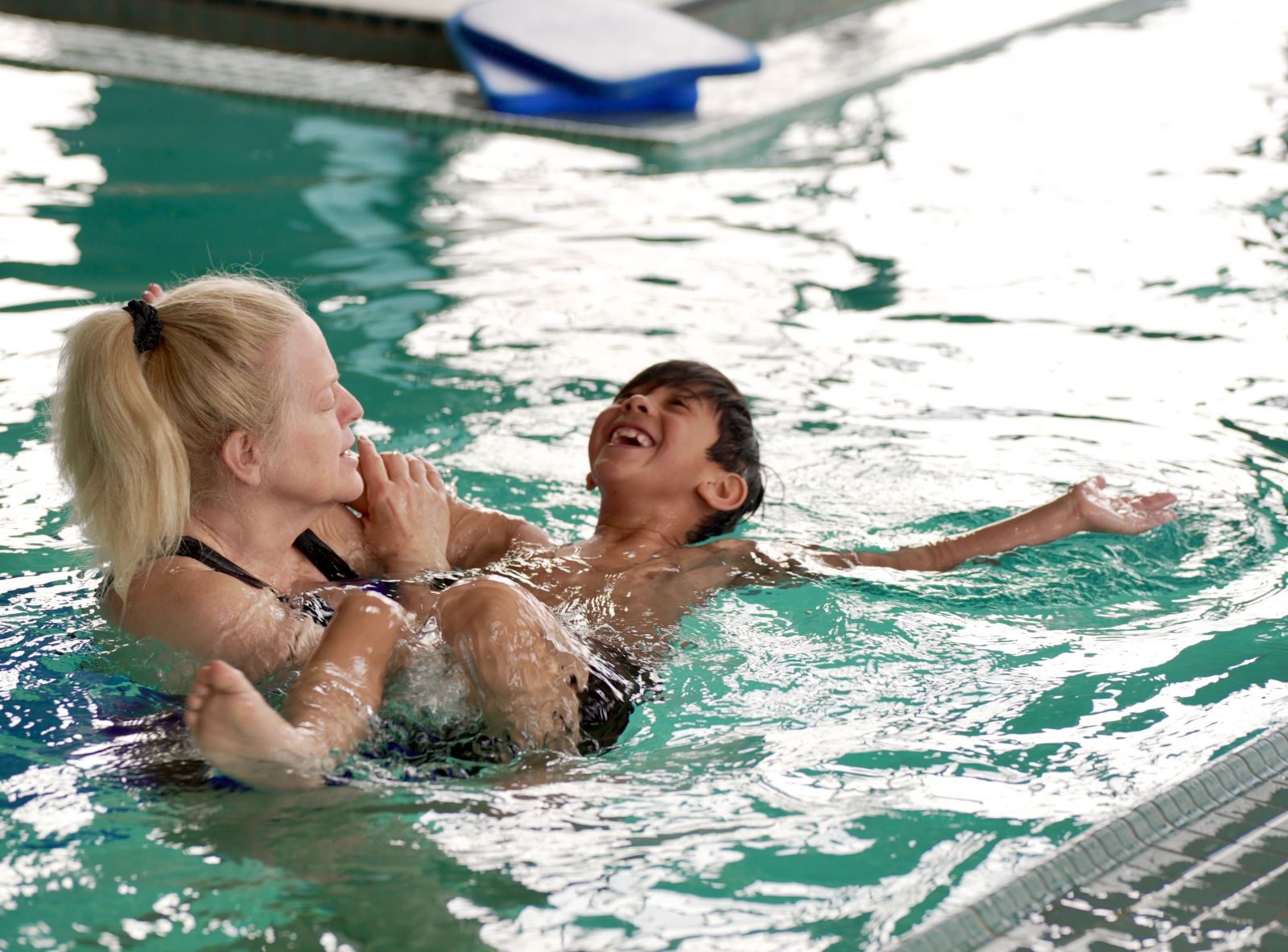 swim lesson instructor teaching boy to swim