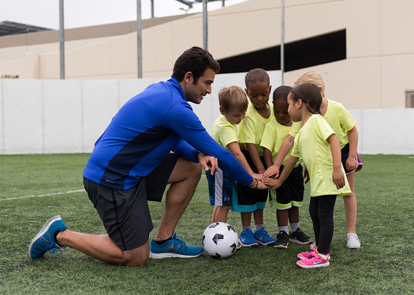 soccer coach and little soccer players in a huddle